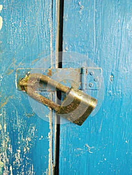 An old padlock that locks a dark blue door