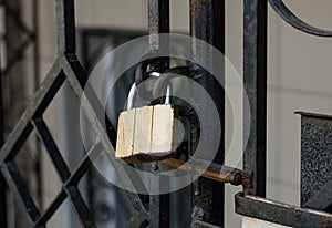 Old padlock. A padlock hangs on the railing. Rusty metal. Closed door.