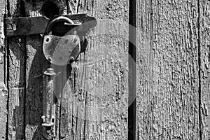 An old padlock on an old wooden door. Black and white image.