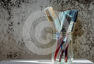 Old paint brushes on grungy wall background