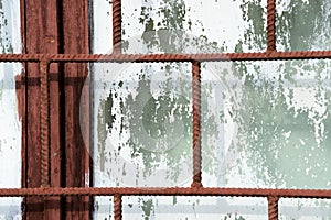 Old painted window behind rusty grate