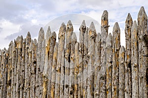 Old paling of sharpened logs on sky background