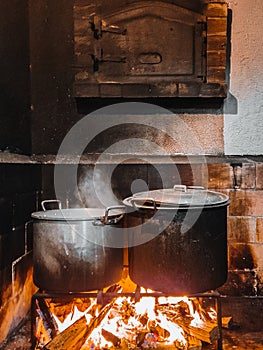 Old pans simmering on a rustic fireplace