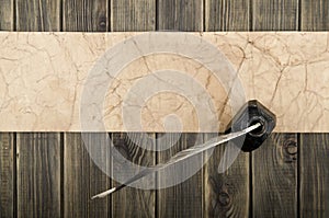 Old paper, inkpot and feather on wooden background close up. View from above