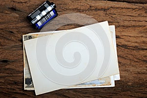 Old paper photo frame with camera film on wood background