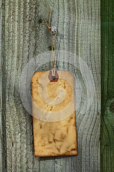 Old paper tag with string on wooden fence