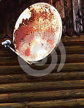 Old parabolic offset antenna attached to the wall of a wooden wall. photo