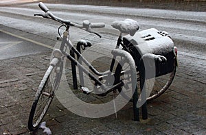 Old parking bicycle under snow at street. Abandoned bike.