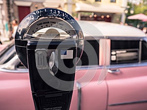 Old parking meter and a vintage pink car in the background