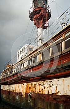 Old and partial rusty houseboat on Copenhagen canal with cloudy grey sky
