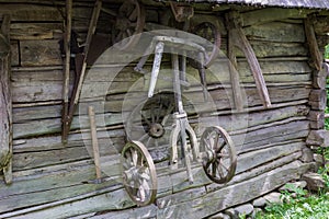 Old partly broken rural wagon undercarriage hangs on wooden wall