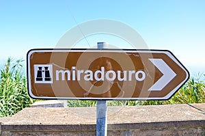 Old, partly damaged brown tourist sign saying miradouro in Portuguese. Information signs. Marking system. Arrow with a symbol of