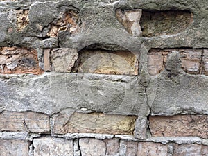 Old partly destroyed red brick wall with crumbling plaster outdoors