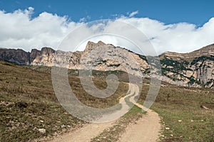 Old path through mountains. Trekking mountain trail. Bright atmospheric minimalist alpine landscape with stony footpath among