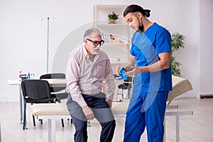 Old patient visiting young male doctor in blood sampling concept