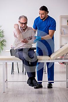 Old patient visiting young male doctor in blood sampling concept