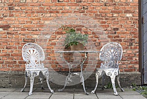 Old, patinated garden furniture against brick wall. photo