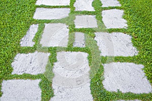 Old paving in a public park made with irregularly shaped stone blocks in a pedestrian zone and fresh green lawn