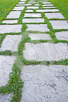 Old paving in a public park made with irregularly shaped stone blocks in a pedestrian zone and fresh green lawn