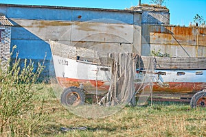 An old peeling fishing boat stands on the shore.