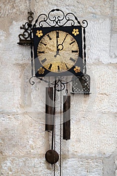 Old pendulum clock on the white stone wall