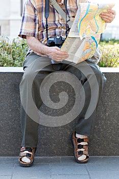 Old pensioner in socks and sandals searching destination on map