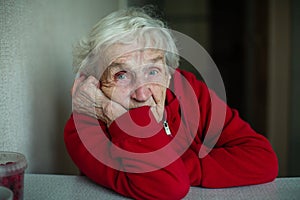 An old pensioner woman in her house, closeup portrait.