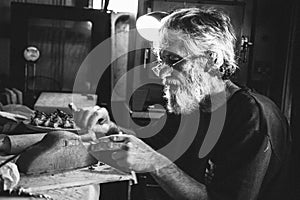 Old pensive man seating in shed making clay pottery