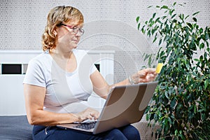 Old people and modern technology concept. Portrait of a 50s mature woman hand holding credit card, using online internet payment a