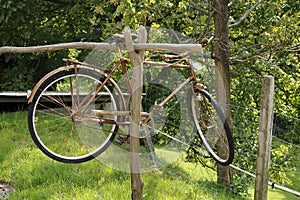 Old person, rusty bicycle , hangs on a wooden beam