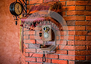 Old phone on the brick wall under the clock. decoration