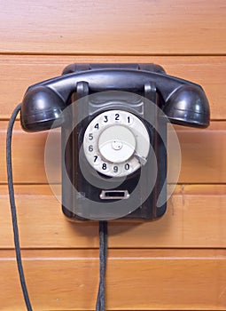 Old phone with dialer disk on wooden background