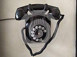 Old phone hanging on the wall. Black color. Vintage photo