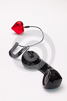 Old phone reciever and cord connection with red heart. photo