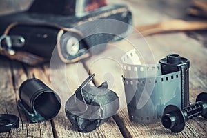 Old photo film rolls and cassette, vintage camera on background.