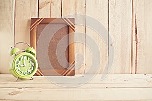 Old photo frame and clock on wooden table over wood background