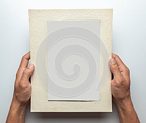 Old photo in frame in the hands of man. Empty template for picture, mock-up. Gray background