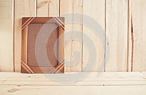 Old photo frame on wooden table over wood background