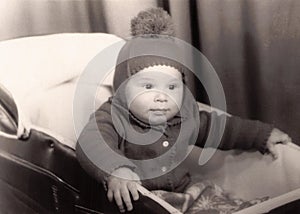 Old photography of a little baby boy in a pram