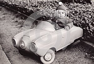 Old Photography of a little girl in a toy car