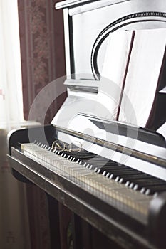 Old piano with sheet music and spectacles lying on the keyboard