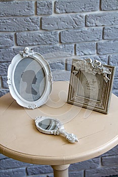 Old picture frames, lying mirror on the table with grey brick wall background remote view