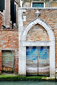 Old picturesque wooden door in venetian canal, Venice