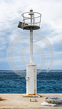 Old pier with a lighthouse beacon and calm sea.