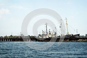 The old pier with rusty ships. Boats are at the broken pier. Repair docks with old bollards