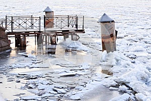 Old pier in winter. Frozen river.