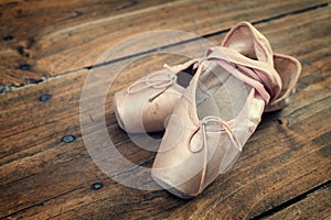 Old pink ballet shoes on a wooden floor