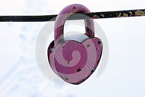 old pink lock in the shape of a heart covered with snow