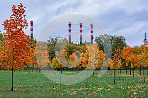 Old pipes of a thermal power plant against the background of the sky and trees in early autumn