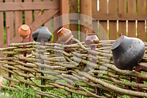 Old pitchers on a wooden fence. Decorative elements of landscape design under the antiquity.